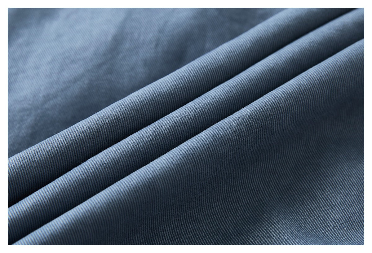 Close-up of blue fabric draped in folds, showing its fine diagonal weave.