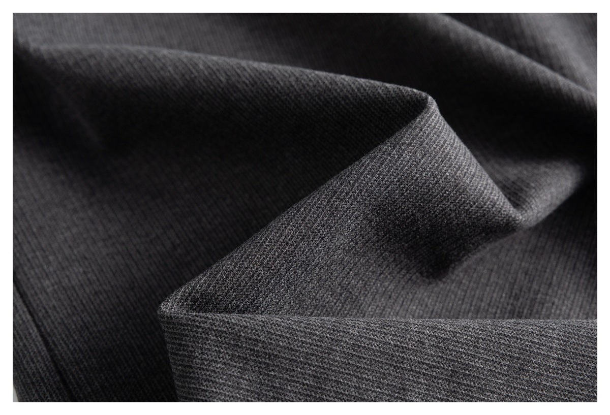 Macro view of the fine, subtly textured charcoal gray trouser fabric folded into soft ridges.