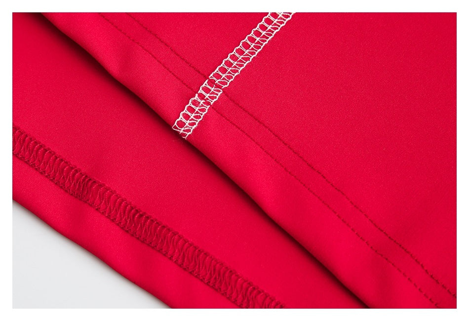 Close-up of red garment fabric with parallel hem stitching and contrasting white overlock seams.