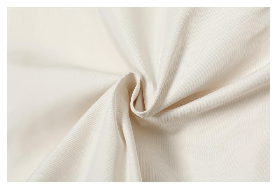 Close-up of ivory fabric gathered into a twist, showing its fine woven texture.