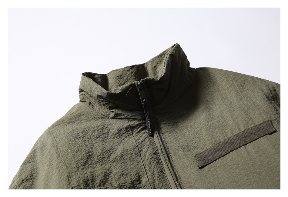 Close-up of the olive jacket's raised collar, front zipper, and horizontal chest trim.