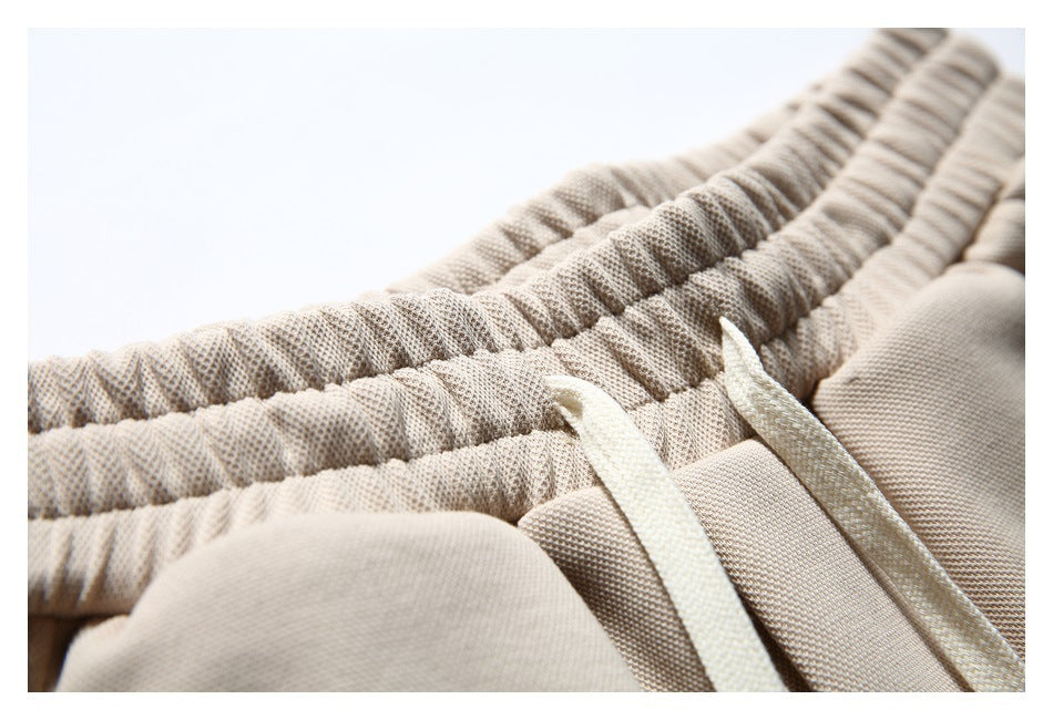 Close-up of the gathered elastic waistband and drawstring openings on beige shorts.
