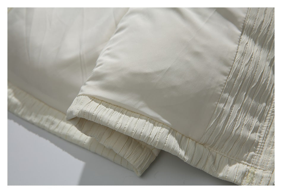 Close-up of the smooth ivory jacket lining beside a textured elasticized cuff.