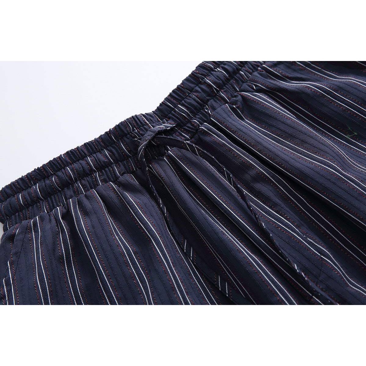 Close-up of navy pinstriped shorts showing the gathered elastic waistband and drawstring.