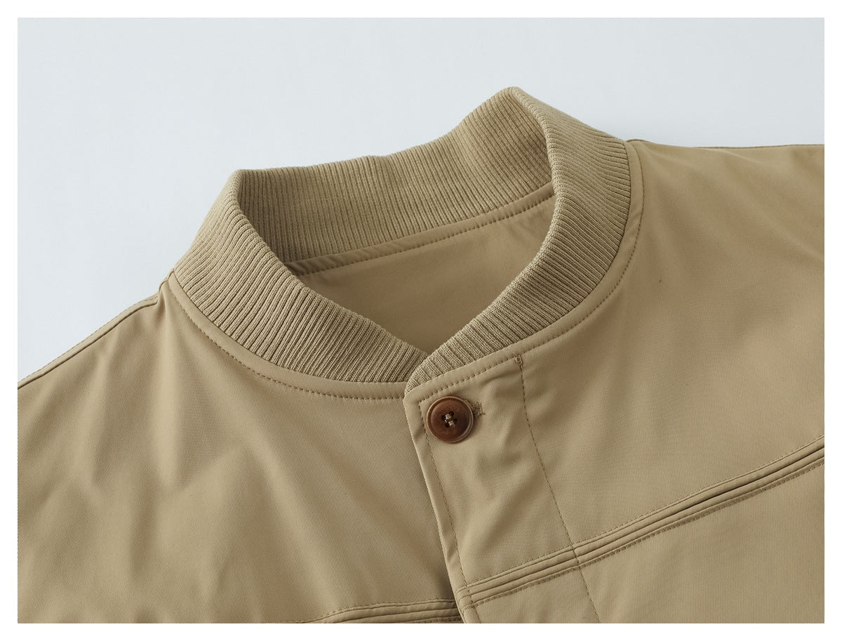 Close-up of a tan jacket's ribbed stand collar, brown button closure and stitched chest seam.