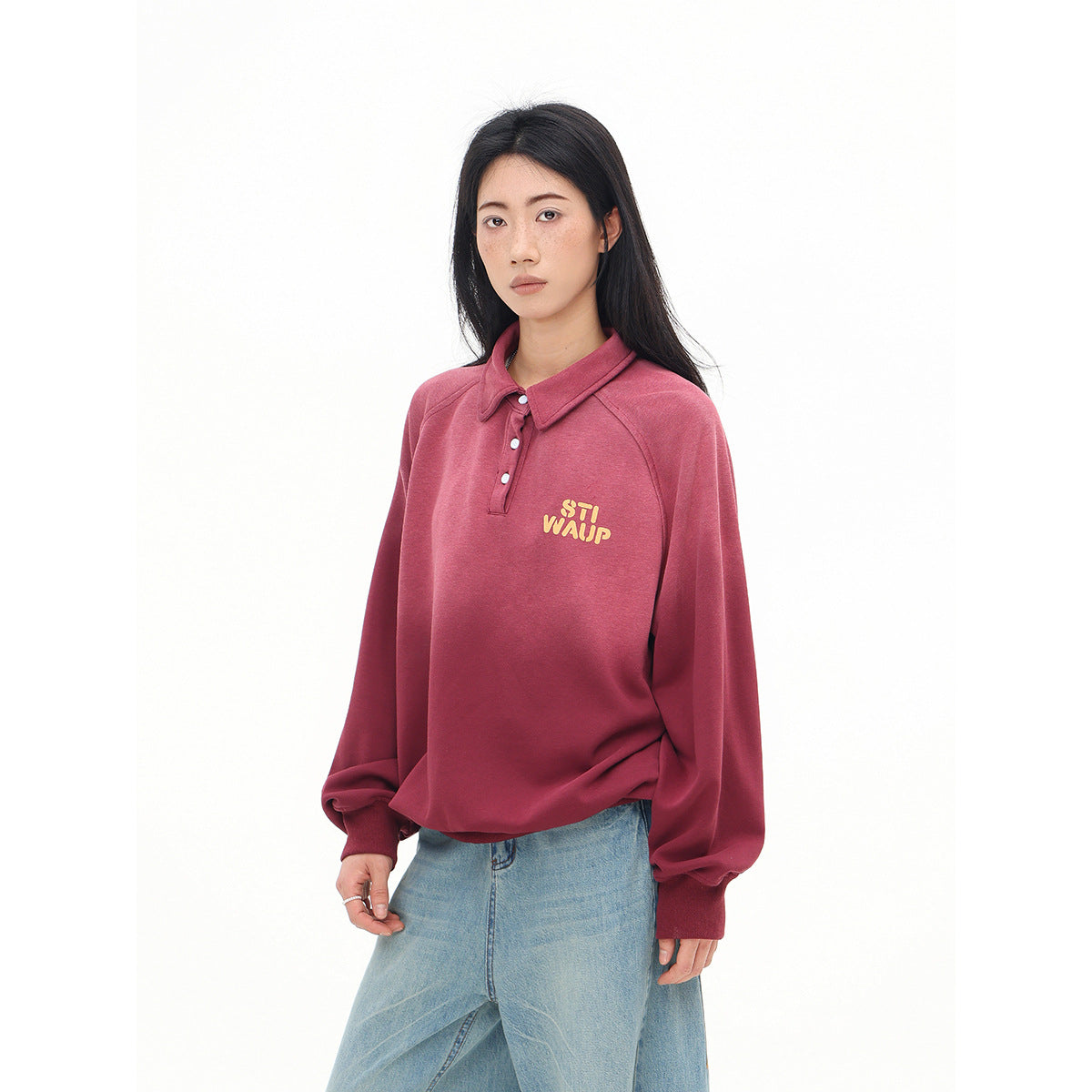 Model wearing a rose-red collared pullover with a short button placket and yellow chest lettering.