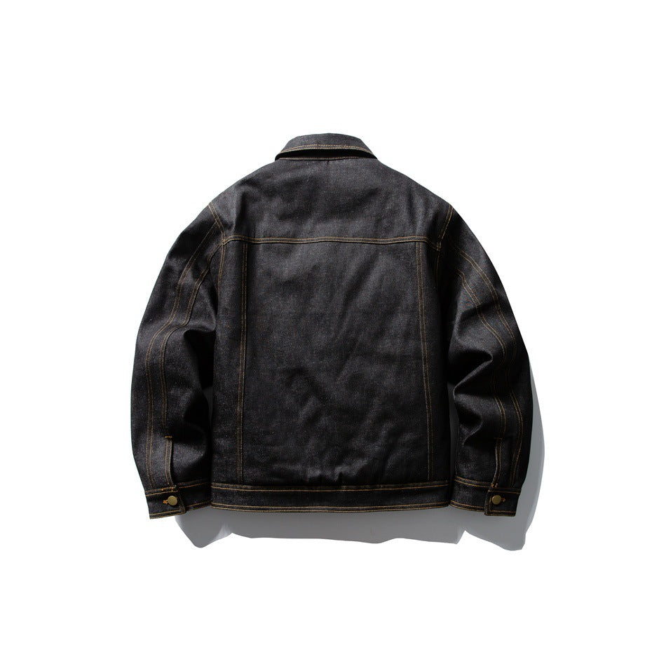 Back view of black denim-look jacket showing yoke seam, vertical seams, golden-tan stitching and button cuffs