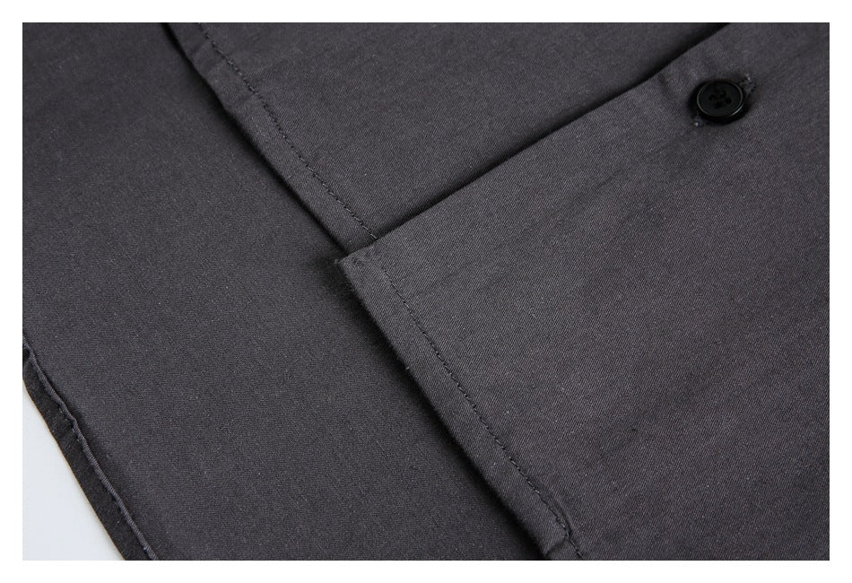 Close-up of a charcoal garment's overlapping front panels, seam, and black button.