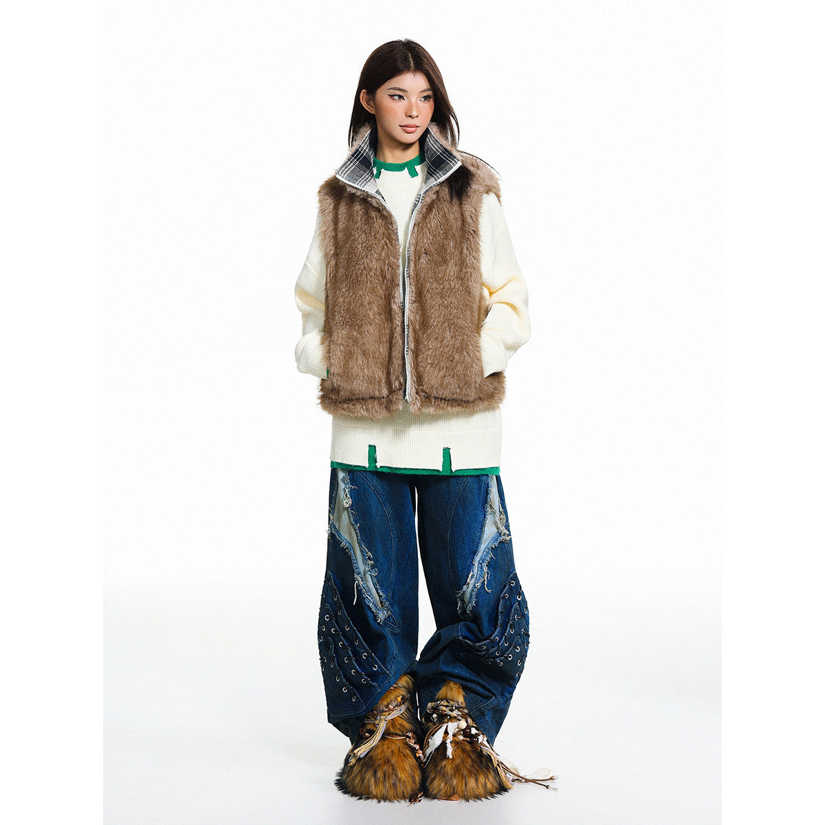 Model wearing a brown furry zip vest with a plaid collar over a cream sweater and wide-leg embellished blue jeans.
