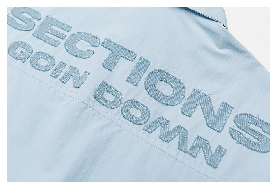 Close-up of raised blue English lettering embroidered across light blue fabric.
