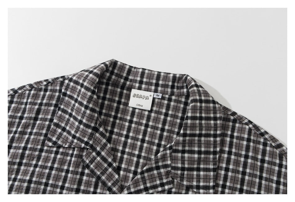 Close-up of the black, gray, and white plaid shirt collar and neck label.