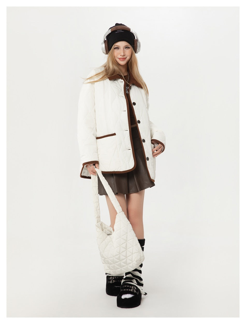 Model wearing a white quilted jacket with brown trim and carrying a matching white quilted shoulder bag.