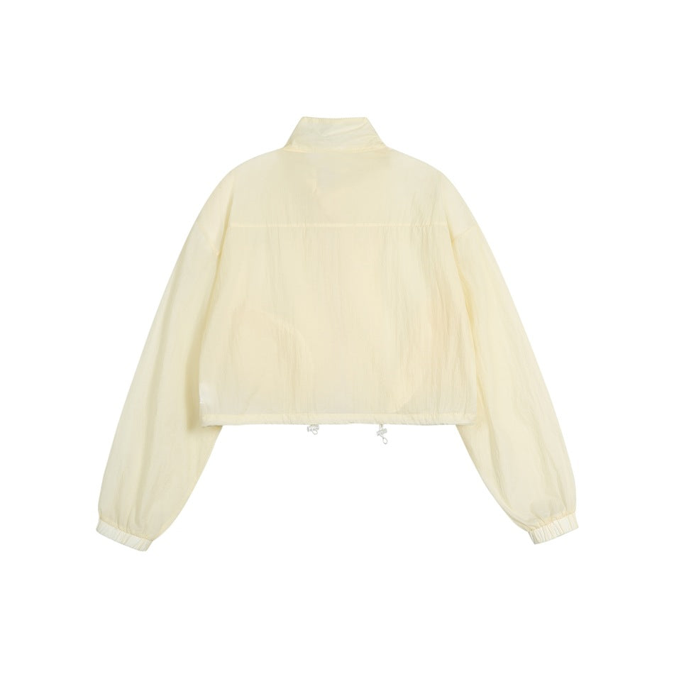 Back view of a pale yellow cropped jacket with a stand collar, long sleeves, elastic cuffs and adjustable hem.