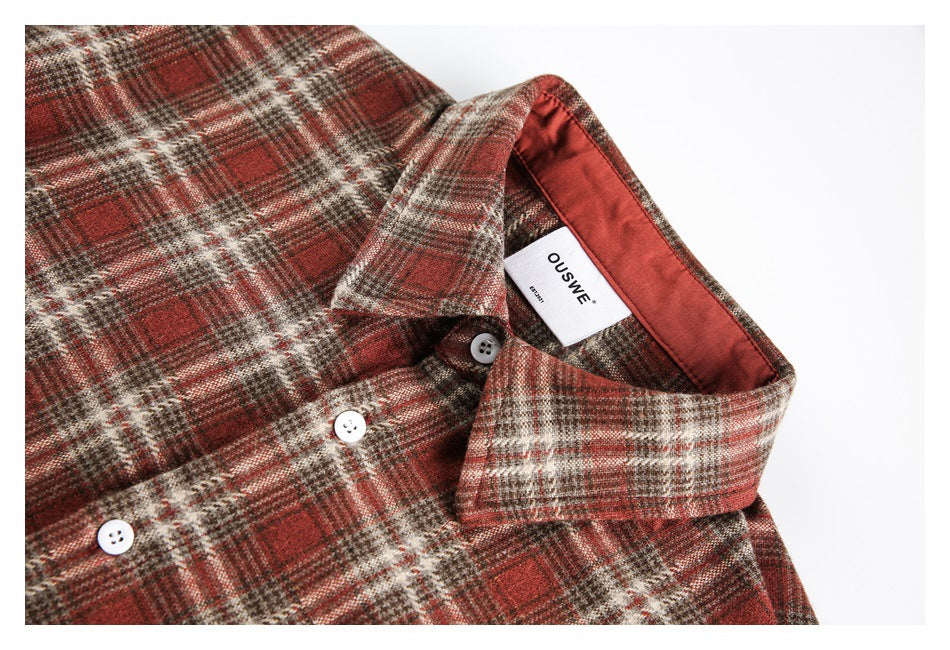 Close-up of the shirt collar, white buttons, plaid fabric and inner neck label.