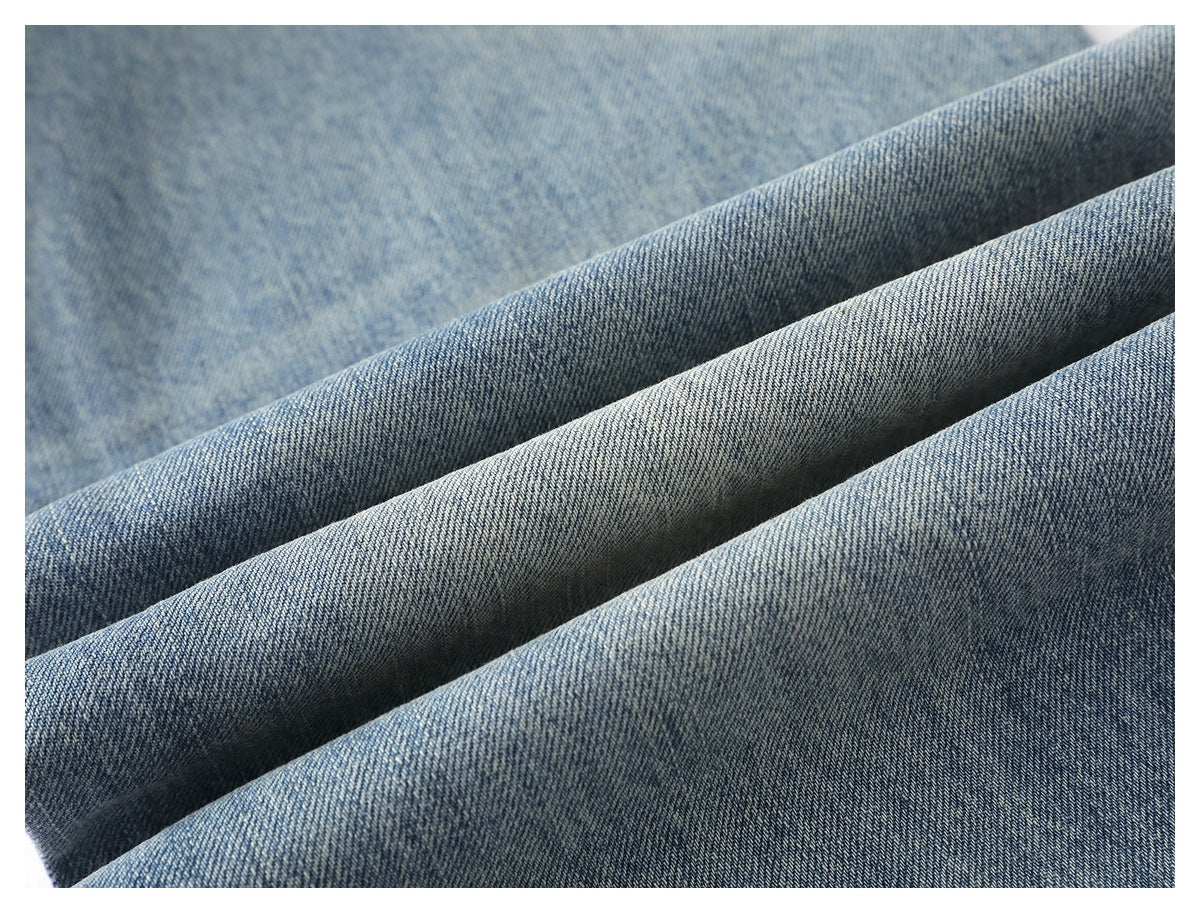 Close-up of blue denim fabric draped in folds, showing its diagonal weave and mottled surface.