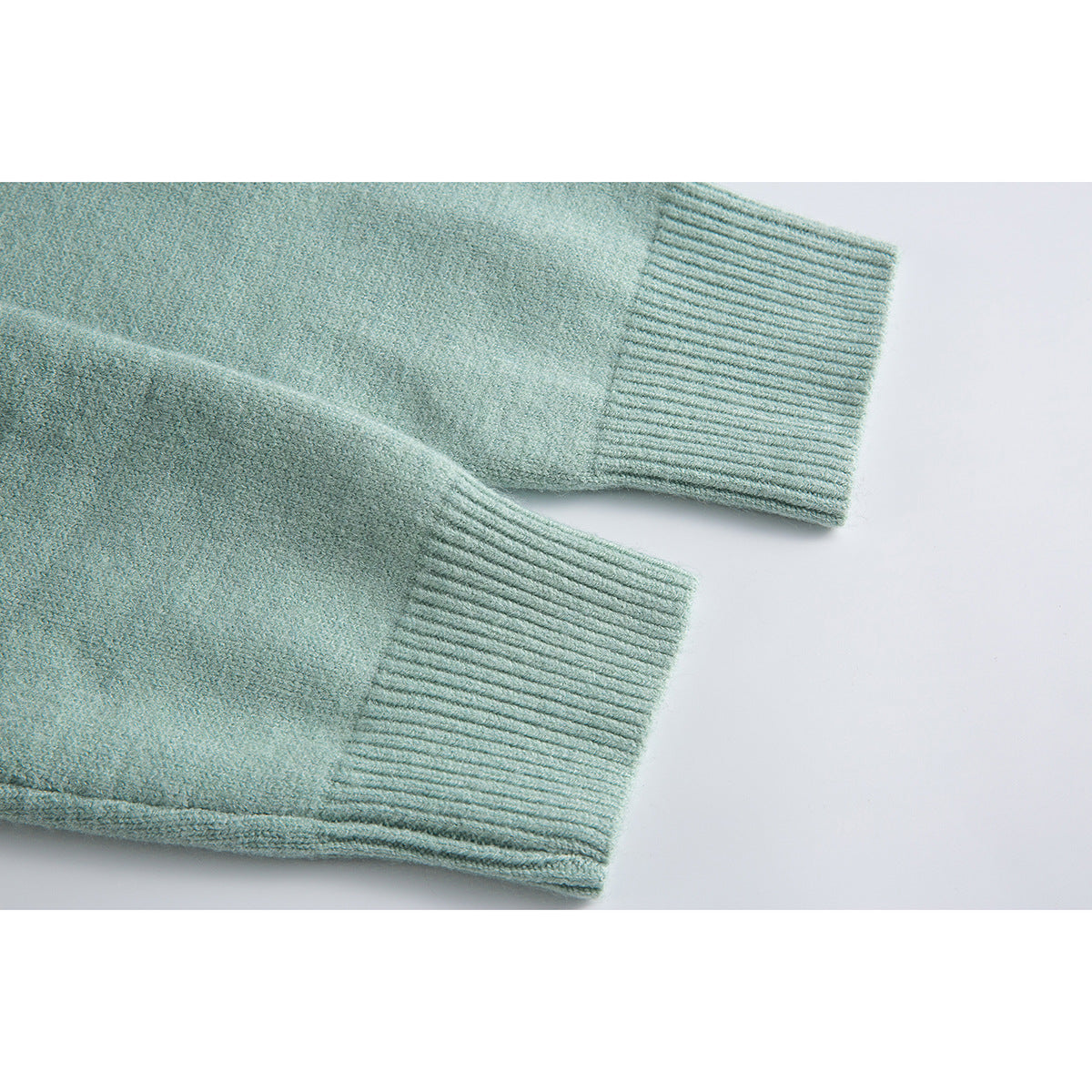 Close-up of two ribbed cuffs on a pale mint-green knit cardigan.