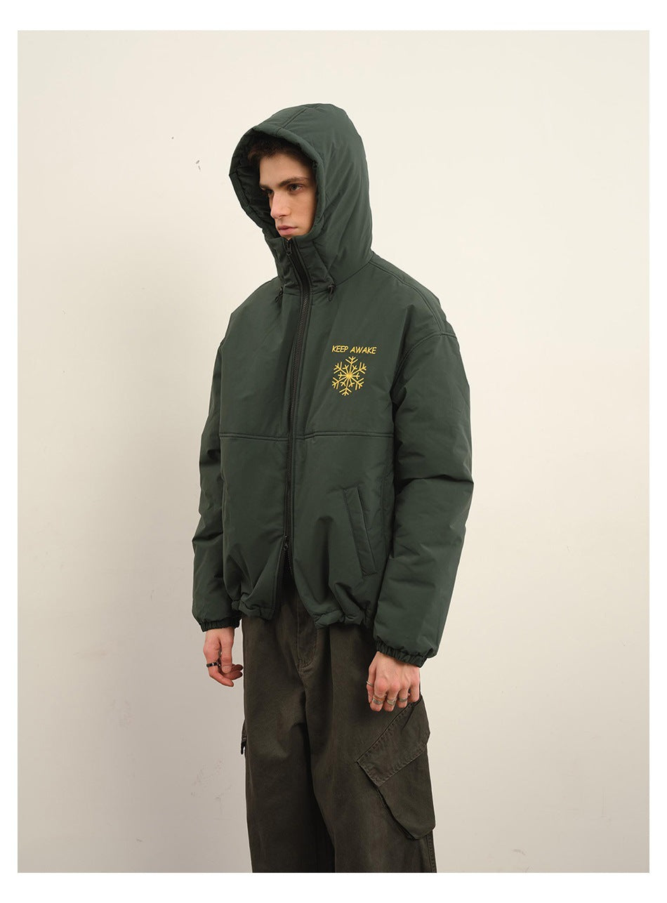 Model wearing a dark green hooded zip jacket with yellow “KEEP AWAKE” lettering and snowflake embroidery.
