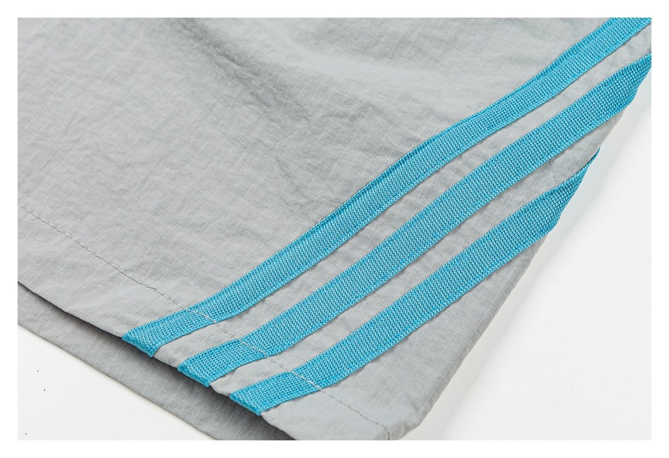 Close-up of three turquoise bands along the hem of light gray shorts.