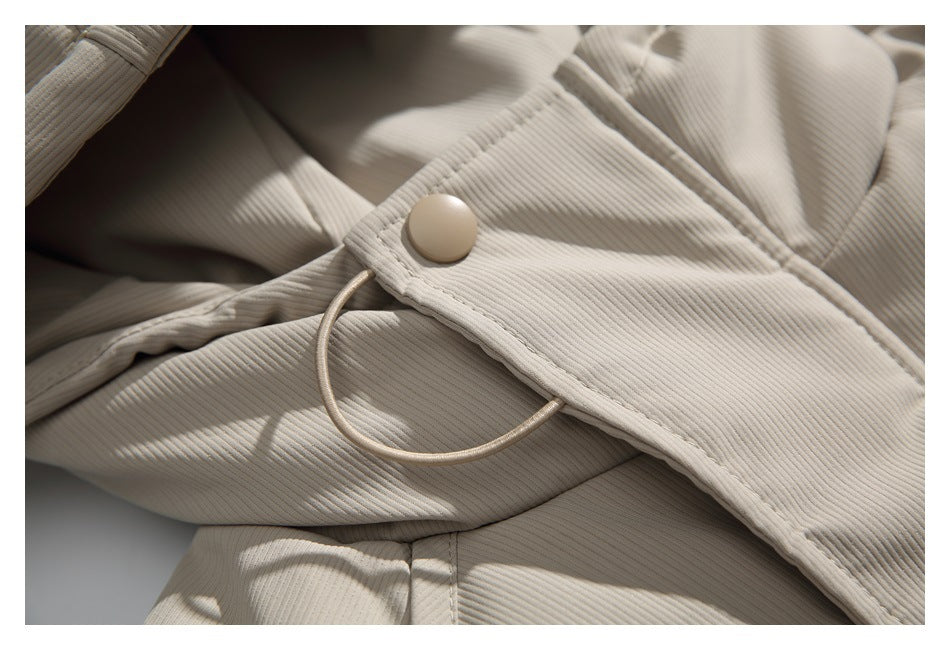 Close-up of a beige snap fastener and loop cord on the jacket's ribbed fabric.