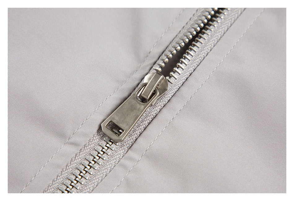 Close-up of the jacket's silver front zipper and light gray fabric.