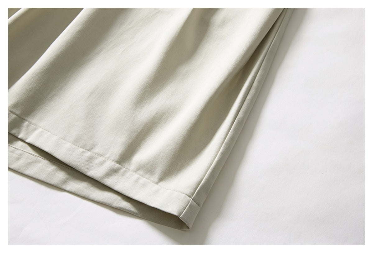 Close-up of the straight stitched hem and side seam on cream trousers.