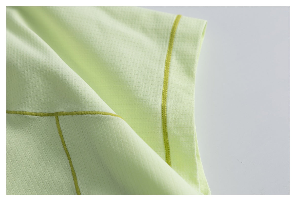 Close-up of pale lime garment edge and panel seams, finished with yellow-green stitching.