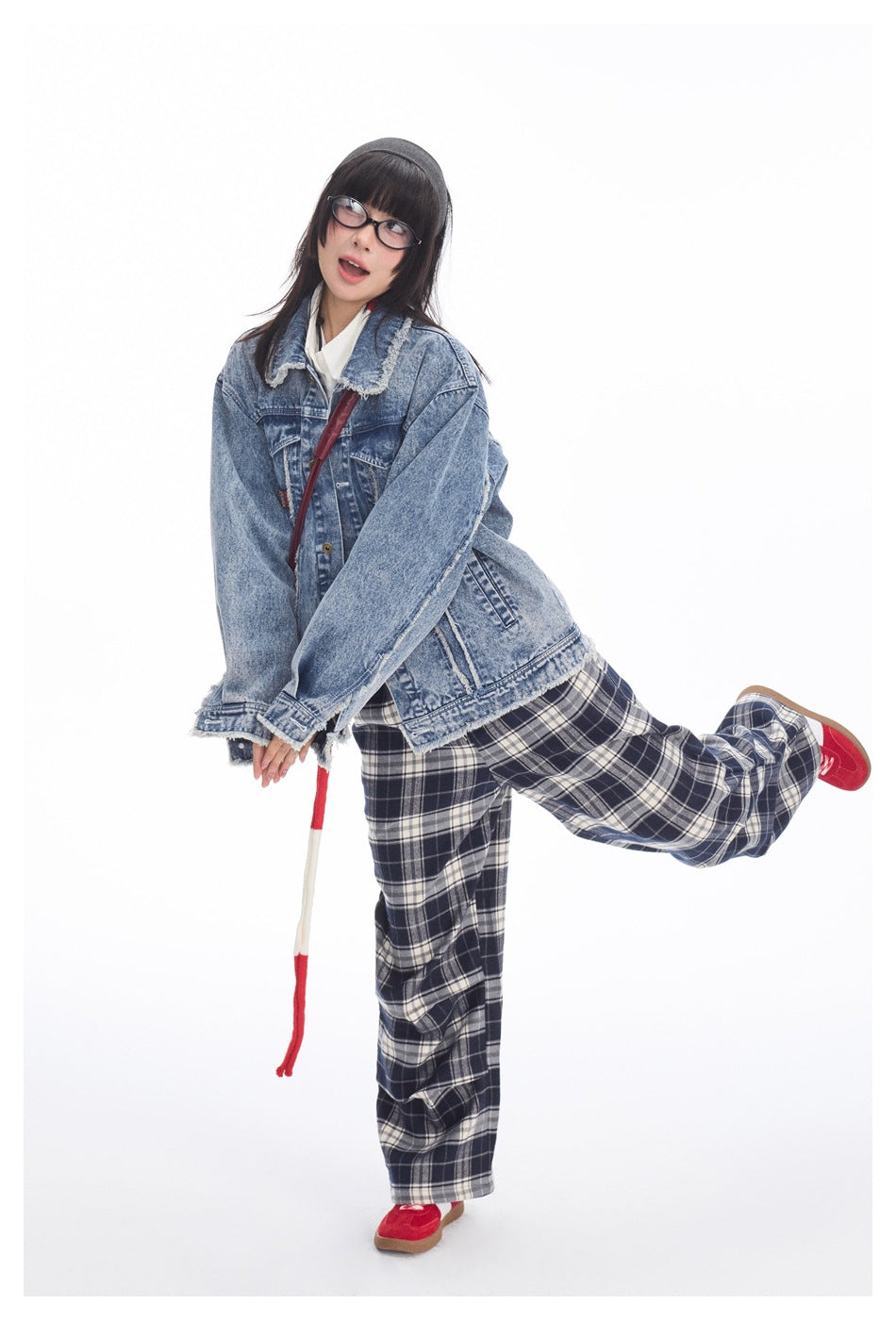 Model wearing an oversized blue denim jacket with frayed edges and navy plaid wide-leg pants.