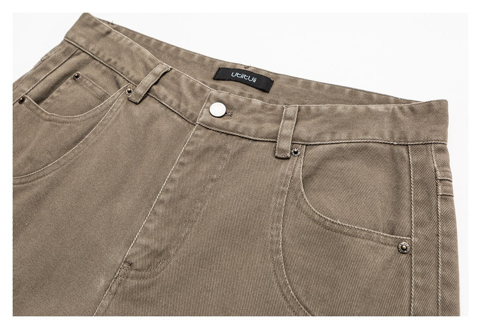 Taupe trousers laid flat, cropped at the hips, with front pockets, belt loops, a button and a black waist label.