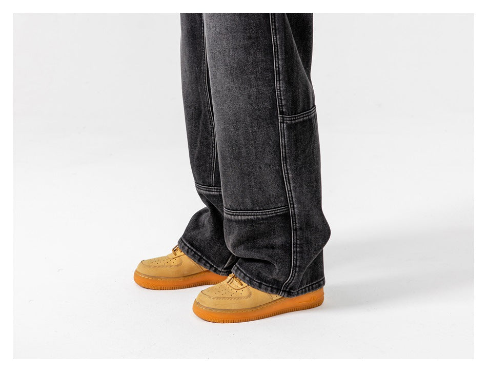 Side view of a person wearing loose black jeans with panel seams and tan sneakers.