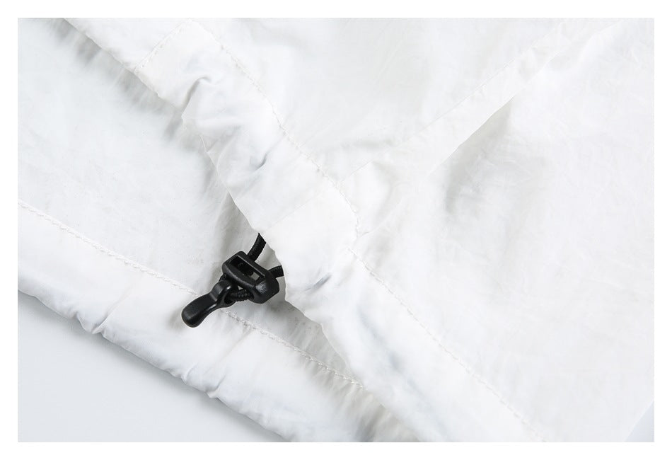 Close-up of a black cord adjuster at the edge of a white jacket.