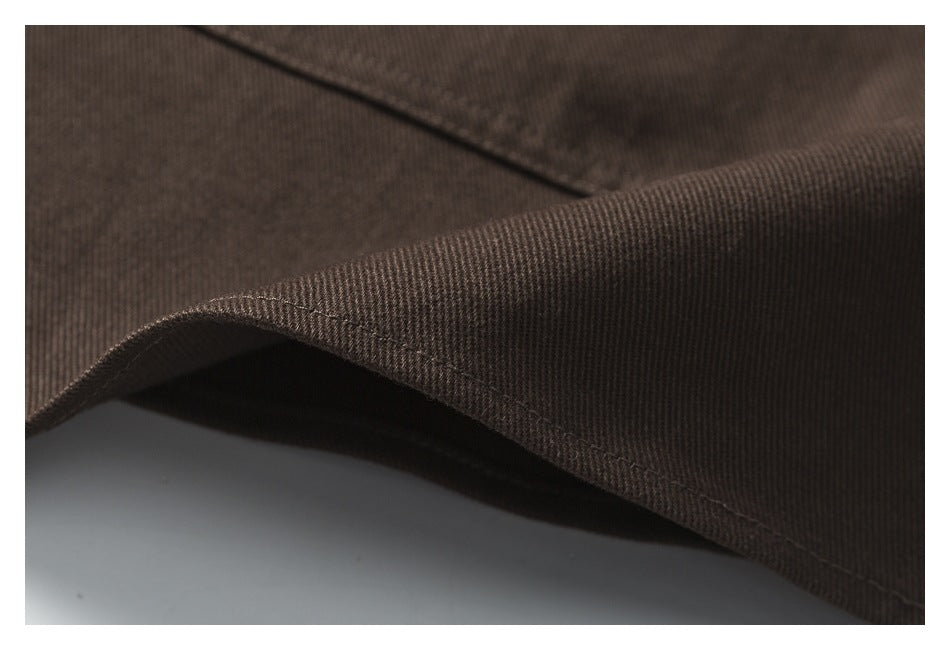 Close-up of a curved hem on dark brown fabric, showing the edge stitching.