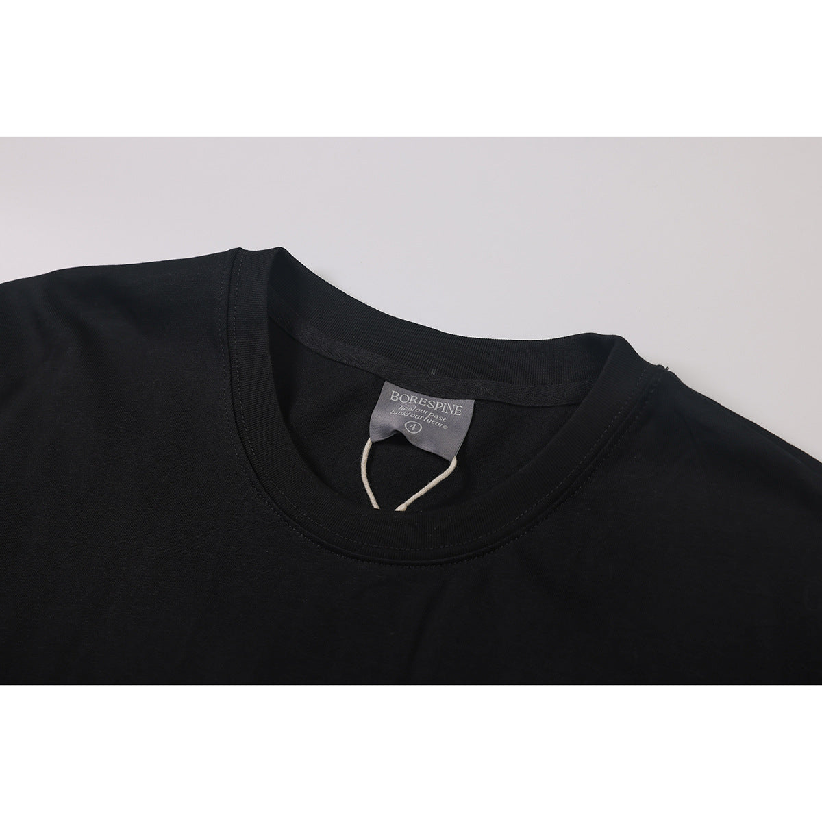 Close-up of a black T-shirt's ribbed crew neck and inner BORESPINE label.