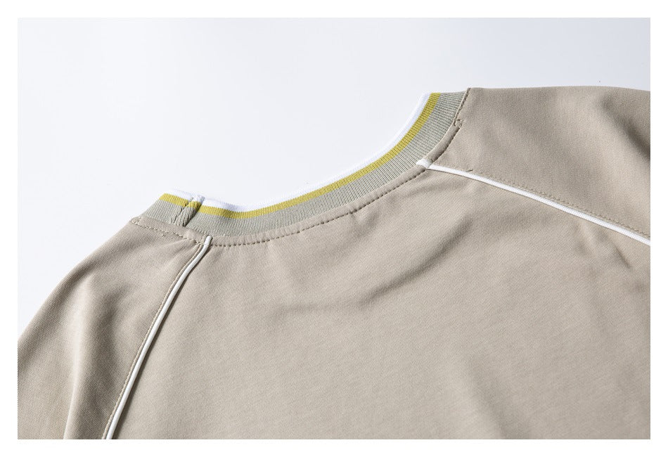 Close-up of a taupe top's ribbed crew neckline with yellow and white stripes and white piping.