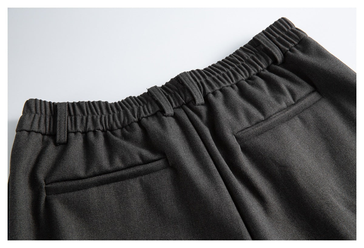 Close-up of the elasticated back waistband, belt loops, and welt pocket on the charcoal trousers.