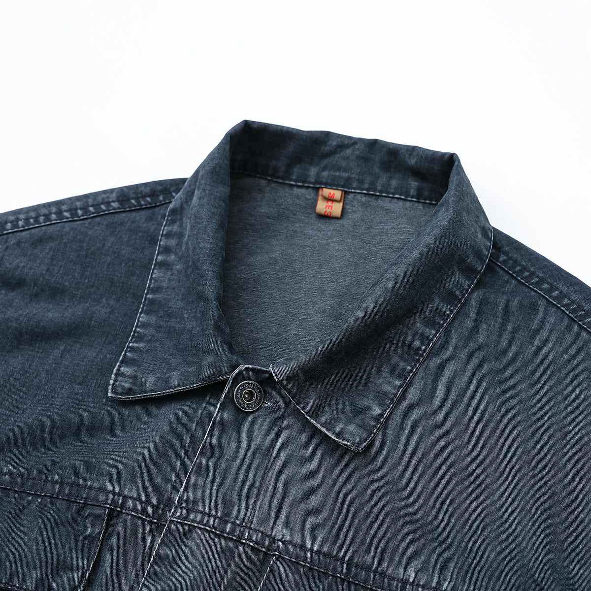 Close-up of a dark blue denim jacket collar, top button, and chest seam.