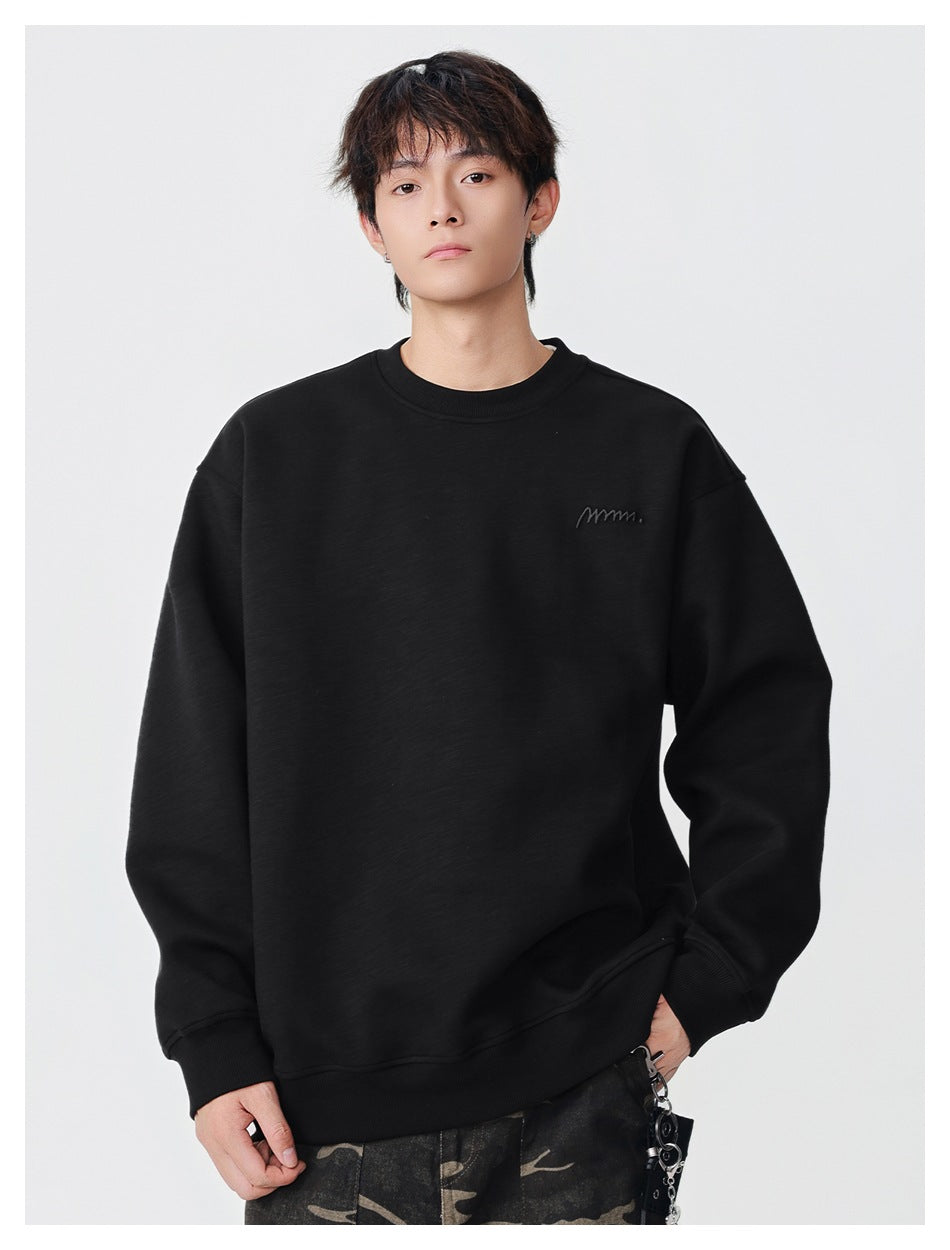 Model wearing a black crewneck sweatshirt with ribbed cuffs and hem and small tonal chest embroidery.