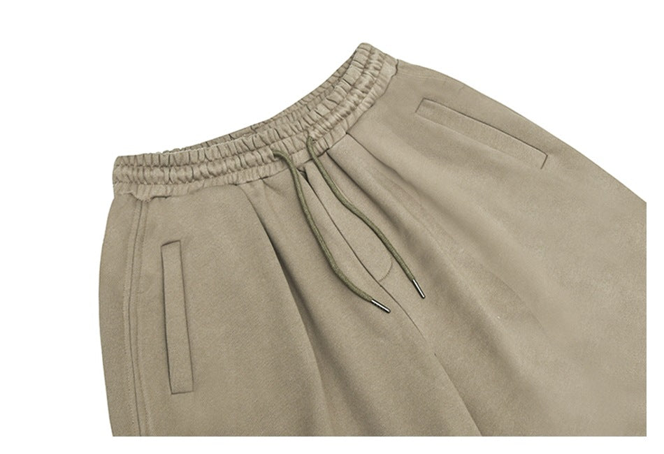 Cropped front view of taupe trousers with an elastic drawstring waist and slim pockets.
