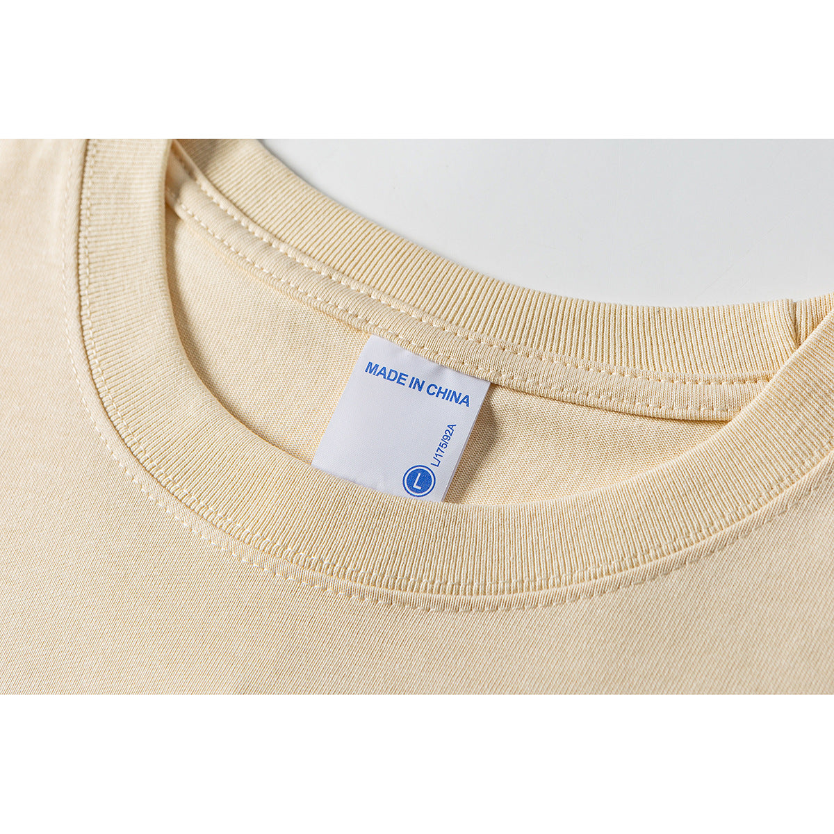 Close-up of a pale yellow T-shirt neckline and sewn label marked “Made in China” and size L.