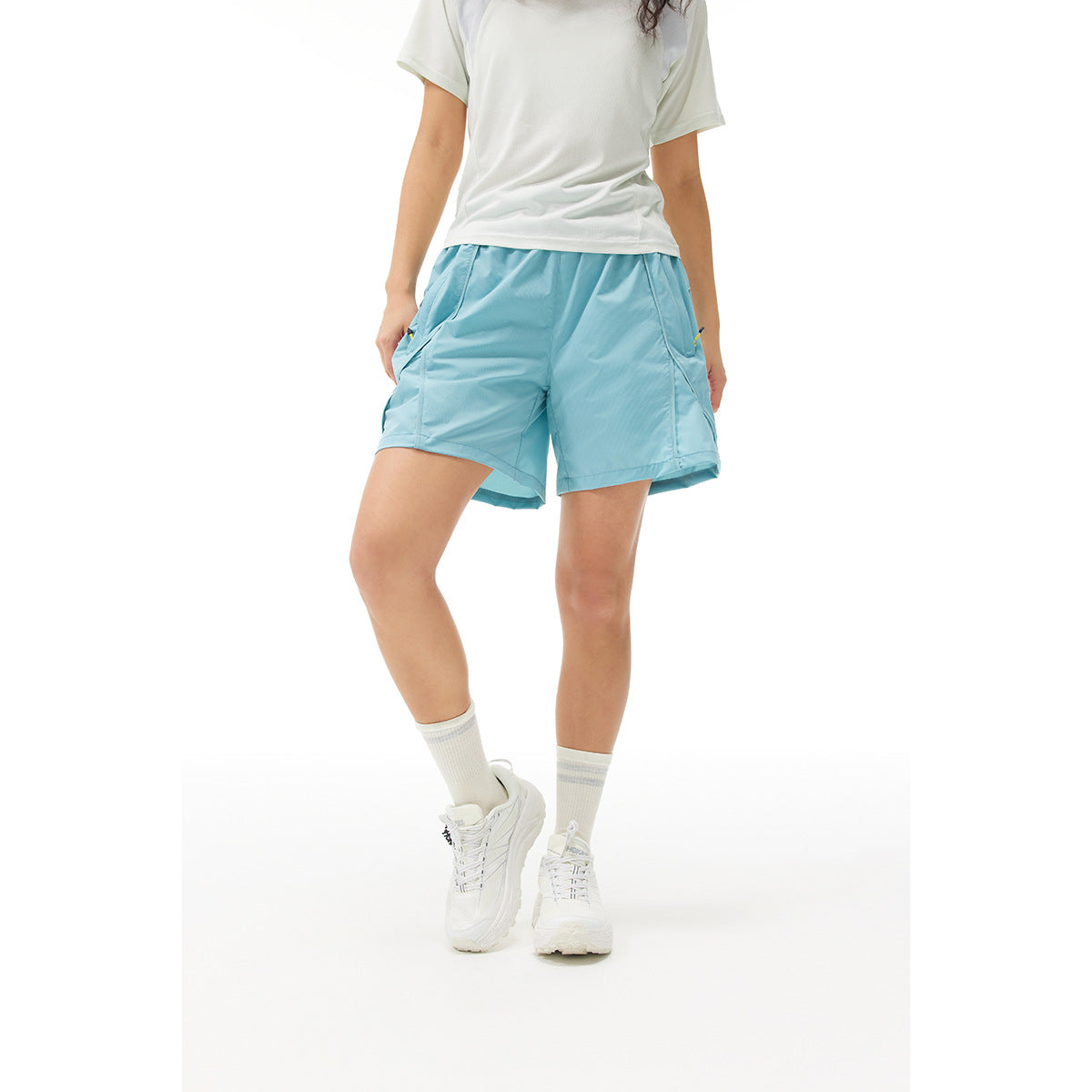 Front view of a model wearing light blue athletic shorts with angled pockets and a white top.