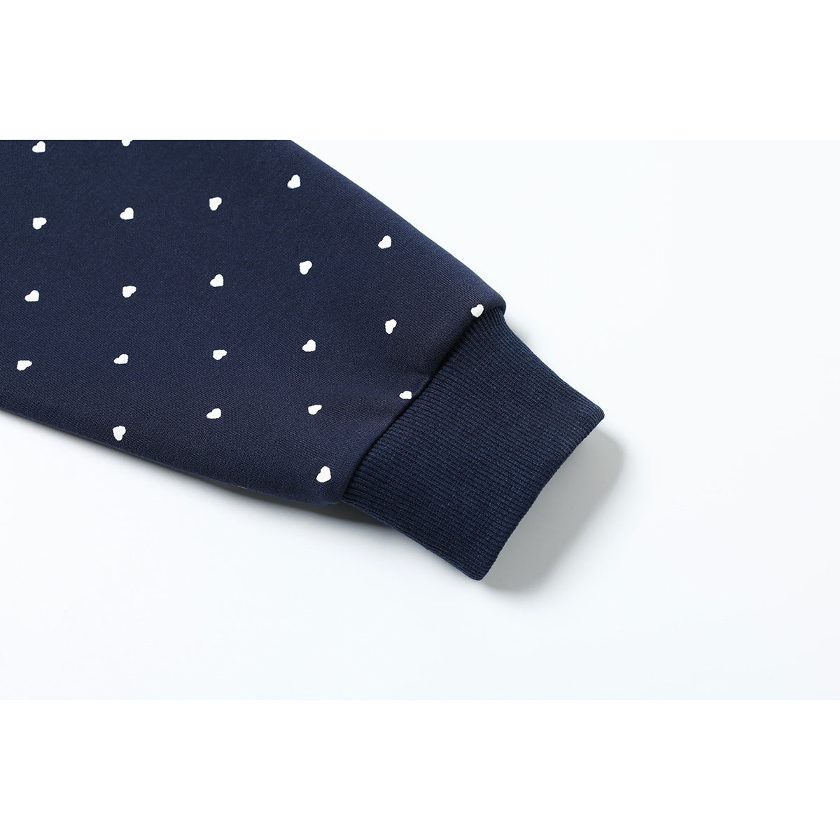 Close-up of a navy hoodie sleeve with small white hearts and a ribbed cuff.