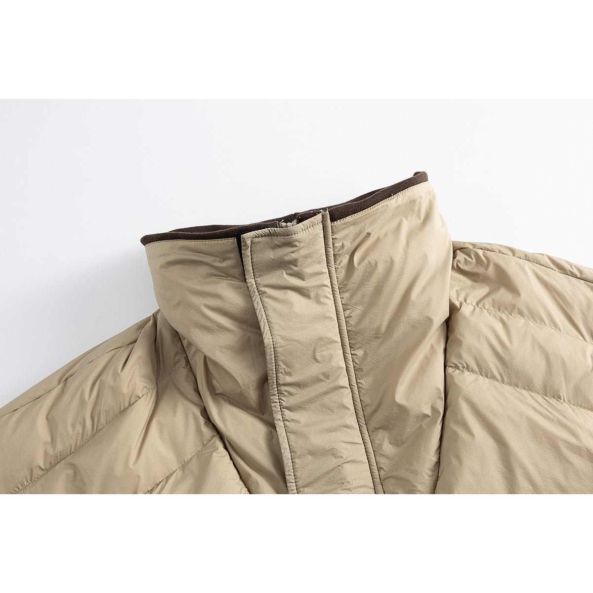 Close-up of a beige padded jacket's high collar and front fastening with dark brown trim.