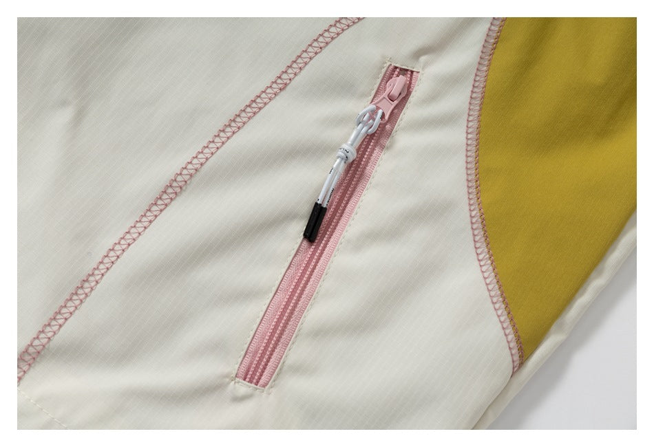 Pink zippered pocket on cream fabric beside a mustard-yellow panel, with visible pink seam stitching.