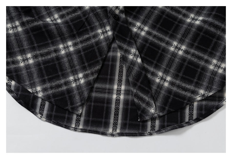 Close-up of the curved hem and button-front area of a black and gray plaid shirt.