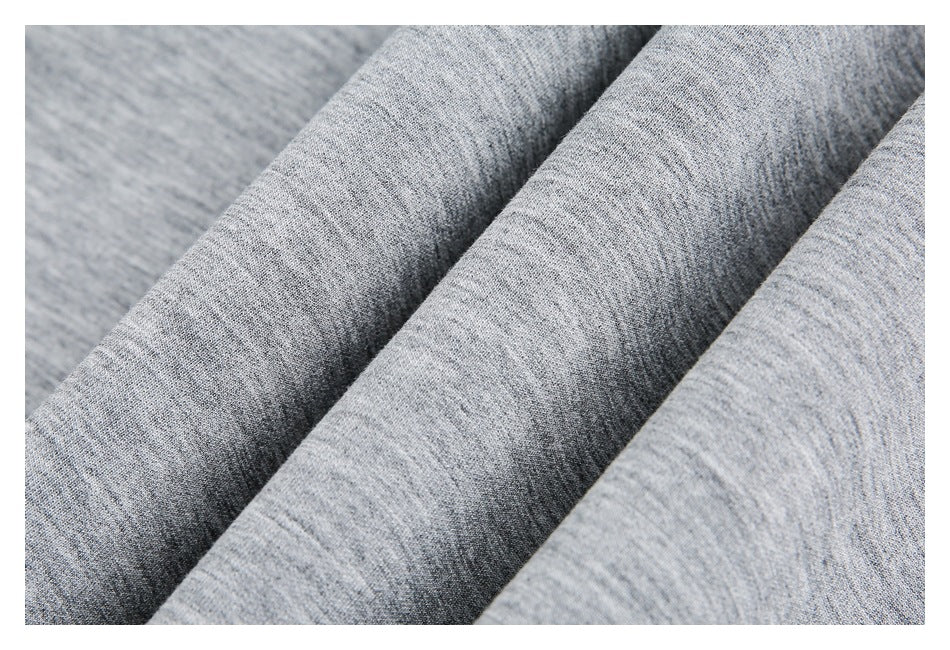 Close-up of heather gray fabric draped in folds, showing its fine marled texture.