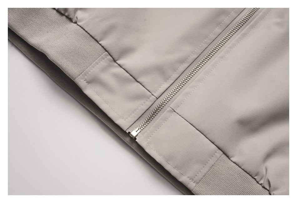 Close-up of a light taupe jacket's front zipper and ribbed hem.