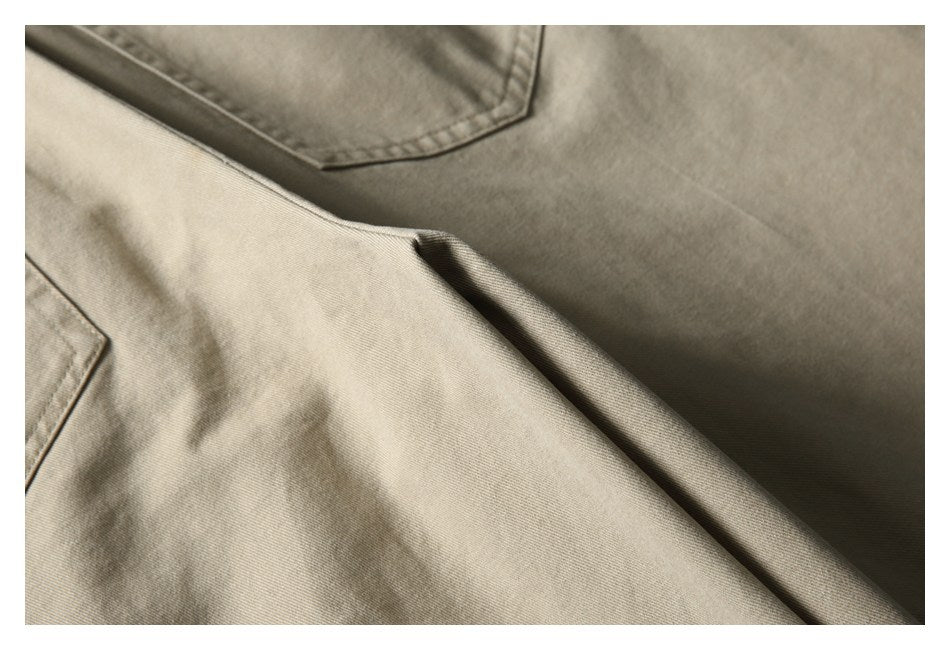 Close-up of beige shorts showing a pocket edge and fabric folds.