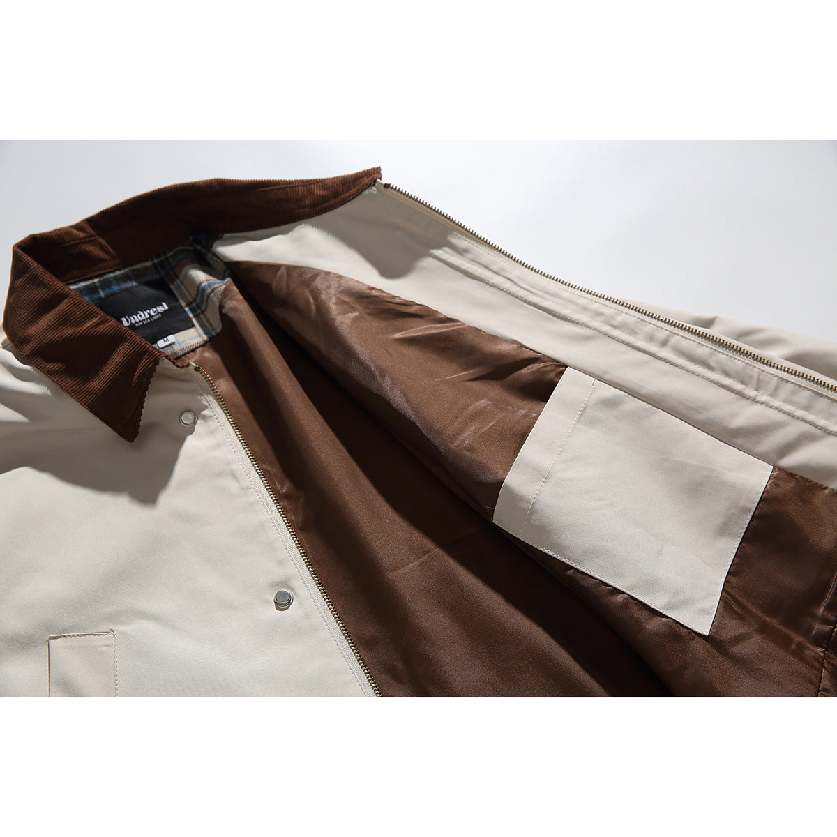The beige jacket is opened to show its brown lining, inner pocket, zipper, and brown collar.