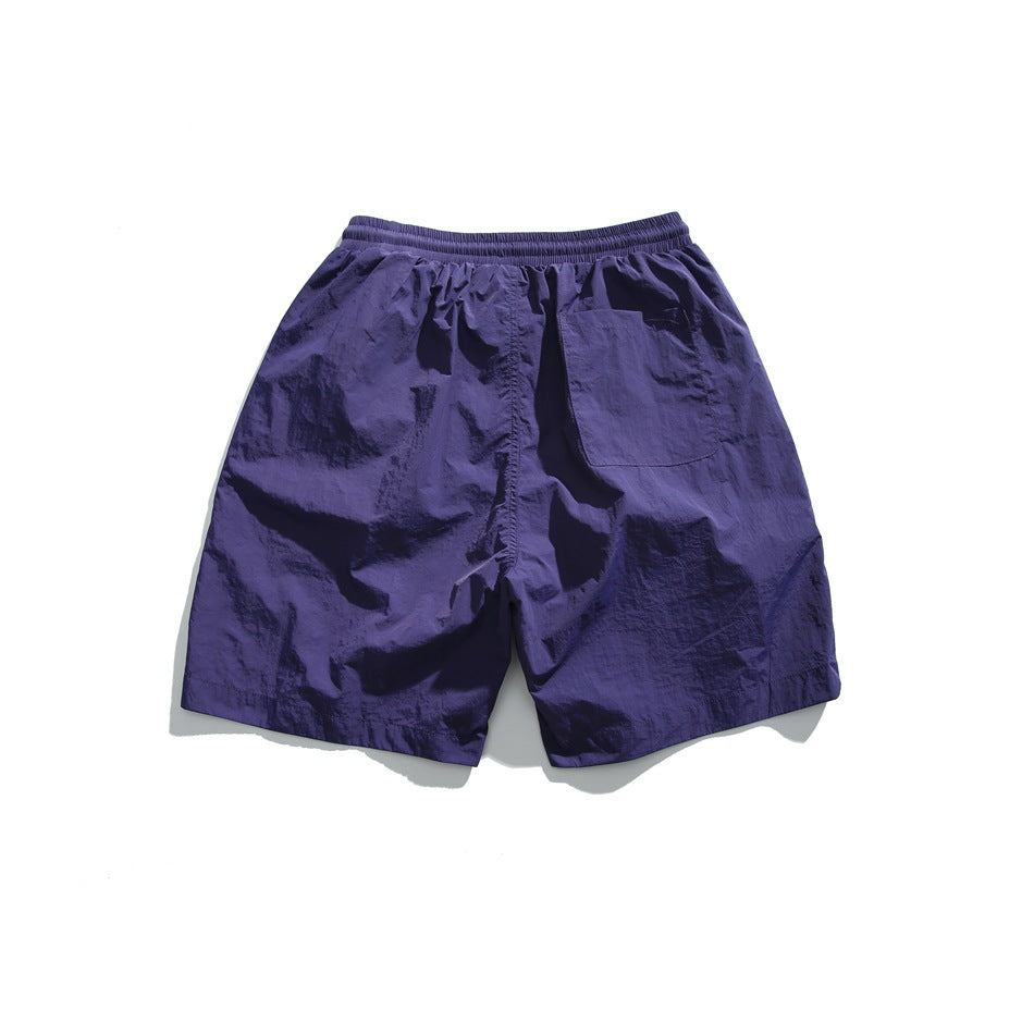 Rear view of purple shorts with an elastic waistband and a single patch pocket.
