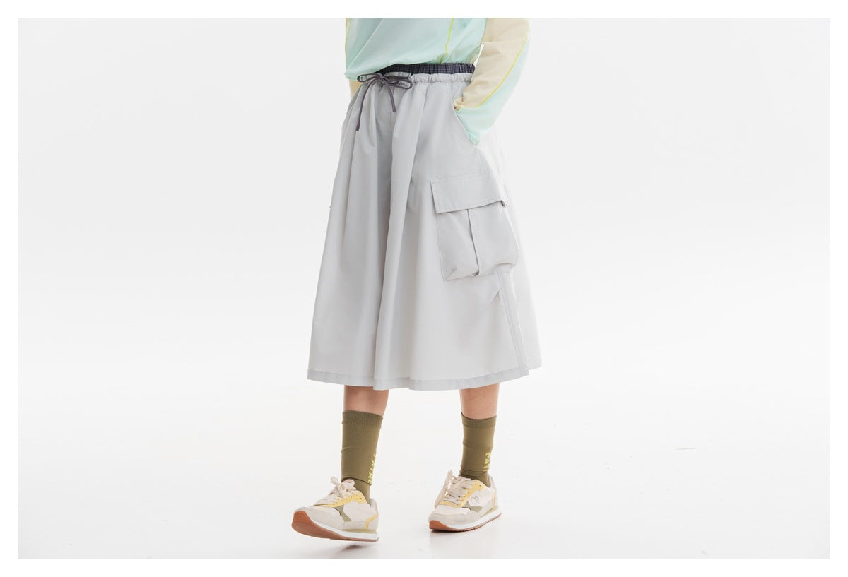 Cropped view of a model wearing a light gray cargo midi skirt with an elastic drawstring waist, front view.