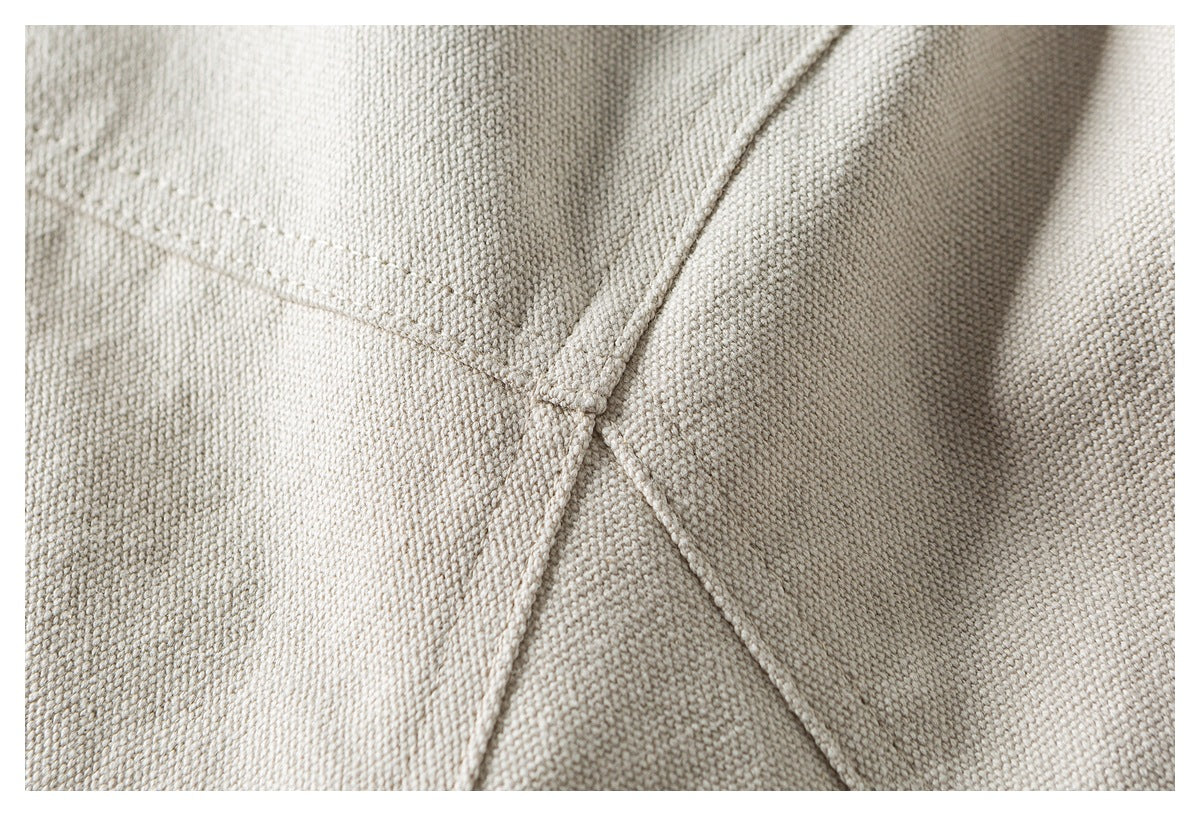 Close-up of intersecting seams on light beige textured woven fabric.